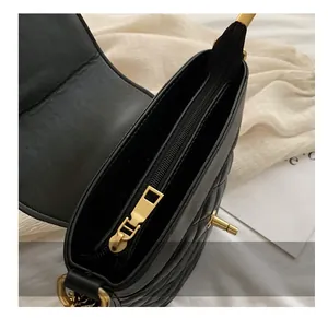 Detail of smooth gold zipper and quilted diamond pattern on black shoulder bag