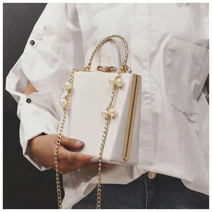 White box clutch bag with gold round handle, bow clasp and elegant pearl chain detail