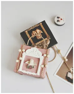 Close-up of vintage square handbag with baroque angel relief and pearl chain detail