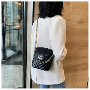 Detail of black quilted bucket bag with gold chain strap worn by a female model