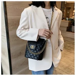 Detail of black quilted bucket bag featuring a gold double-ring clasp and chain strap
