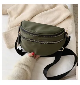 Detail of army green nylon crossbody bag with dual golden zippers and wide strap
