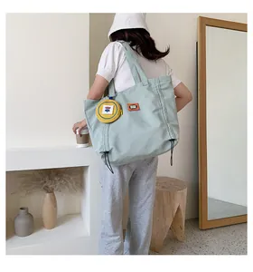 Detail of mint green canvas tote with yellow floral pouch charm and orange patch