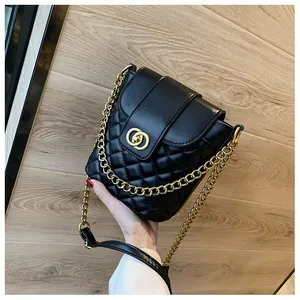 Detail of black quilted bucket bag with gold chain strap and interlocking buckle