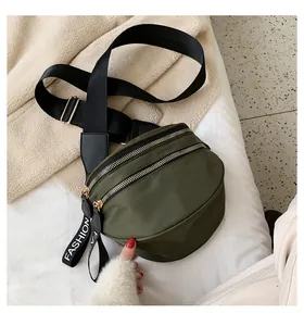 Detail view of army green nylon crossbody bag with dual gold zippers and fashion webbing