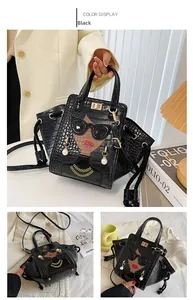 Dettaglio della borsa nera in ecopelle coccodrillo con patchwork chic e manico superiore
