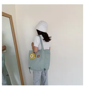 Detail of light green canvas tote bag with yellow floral coin purse and side drawstrings
