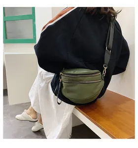 Detail of army green crossbody chest bag with double zippers and wide black strap