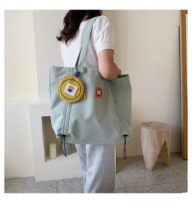 Back view of a large light green canvas tote bag with yellow coin purse and orange tag