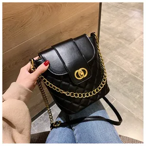 Detail of black quilted leather bucket bag with gold circular lock and chain strap