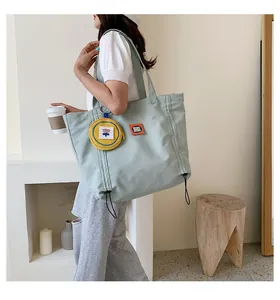 Detail of light green canvas tote bag featuring an orange label and yellow floral coin purse