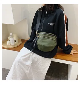 Detail of army green nylon crossbody bag showing dual zippers and FASHION straps