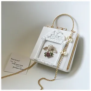 Detail of white square bag featuring angel relief, rose frame, and pearl pendant accent