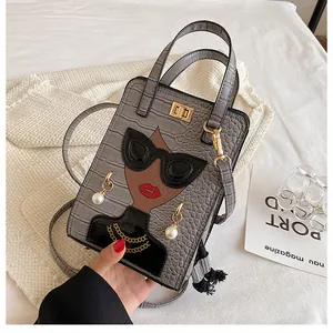 Dettaglio della borsa grigia a motivo coccodrillo con collage moda e fibbie dorate