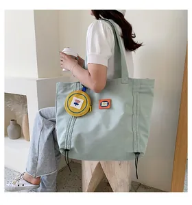 Detail of light green canvas tote bag featuring an orange patch and yellow coin purse charm