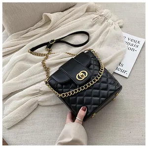 Detail of black quilted bucket bag featuring gold interlocking buckle and chain strap