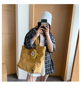 Detail of yellow canvas tote bag with matching round coin purse and decorative drawstring