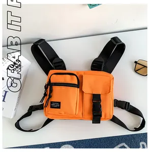 Detail of bright orange tactical chest bag featuring dual front pockets and durable buckles