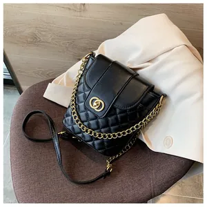 Detail of black quilted bucket bag with gold interlocking buckle and chain strap