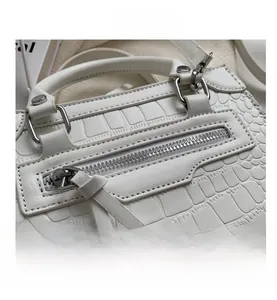 Detail shot of white crocodile embossed texture and silver metal ring on the fashion handbag