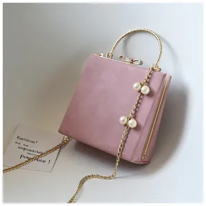 Detail of pink crossbody bag with gold metal handle and pearl-decorated chain