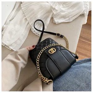 Detail of black quilted shoulder bag featuring round gold clasp and chain strap