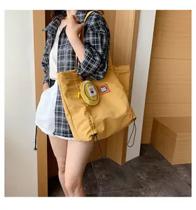 Detail of yellow canvas tote bag with a small flower coin purse and letter logo patch