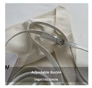 Detail of adjustable leather strap with silver metal buckle on a woven cream bag