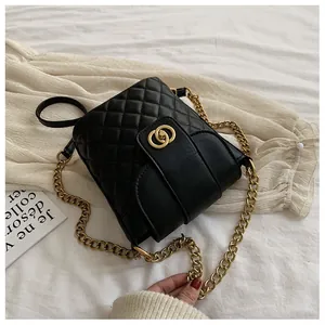 Close-up of black quilted bucket bag featuring a gold metal lock and elegant chain strap