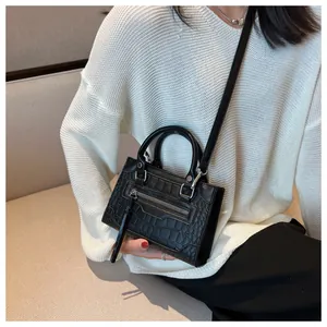 Detail view of black crocodile pattern crossbody bag with fringe zip pocket on a model