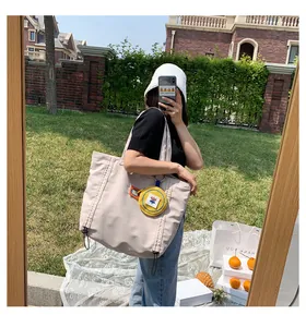 Beige canvas tote bag featuring side drawstrings and a yellow floral coin purse charm