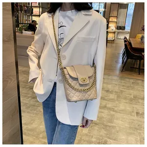 Close-up of beige quilted bucket bag with gold chain strap and interlocking metal clasp