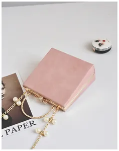 Pink evening clutch with gold metal frame, pearl handle, and crystal bow clasp detail