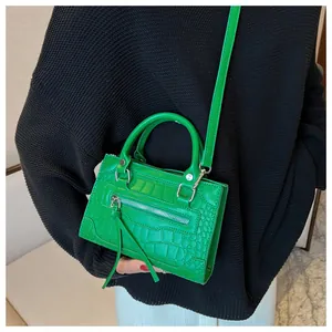 Detail of bright green crocodile embossed mini bag with silver hardware and tassels
