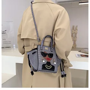 Borsa a mano grigia motivo coccodrillo con dettaglio ragazza cartoon su un trench beige