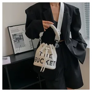 Close-up of a white canvas bucket bag with 'THE BUCKET' text and wide shoulder strap