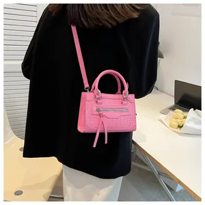 Detail of pink croc-embossed handbag with dual tassels and top handles in office setting