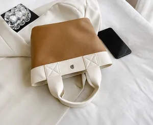 Dettaglio della borsa bicolore in pelle PU con cuciture fini e chiusura magnetica in metallo