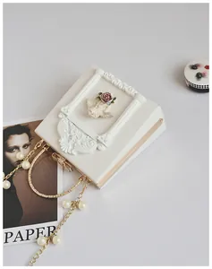 Detail of white vintage bag featuring baroque angel relief and gold metal ring handle