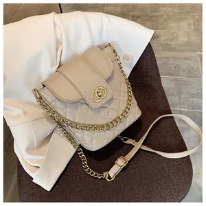 Detail view of beige quilted bucket bag with golden interlocking ring buckle and chain strap