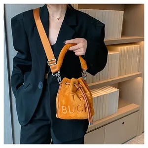 Close-up of orange plush bucket bag with The Bucket lettering and wide shoulder strap