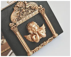 Close-up of vintage black leather bag featuring a detailed golden cherub metal relief