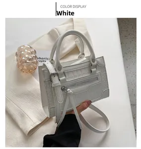 Close-up of white crocodile embossed leather bag with front zipper and strap details