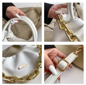 Detail view of white pleated PU bag with chunky gold chain and metallic hardware accents