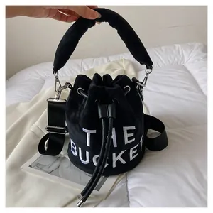 Detail of black velvet bucket bag with white THE BUCKET embroidery and drawstring