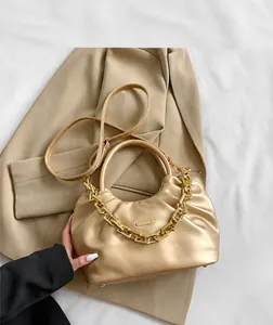 Detailed view of a metallic gold pleated cloud bag with a chunky metal chain handle