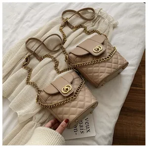 Detail of quilted stitching and gold chain strap on two beige bucket bags for women