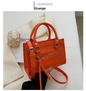 Close-up of orange crocodile pattern PU leather handbag with fringe and zipper details