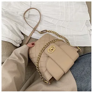 Close-up of beige quilted crossbody bag with gold chain strap and metal lock detail
