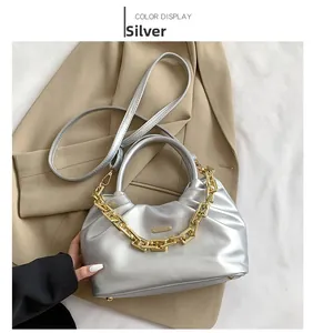 Close-up of a silver pleated PU bag featuring decorative gold chain and leather strap